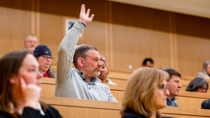 A Cornell community member raises his hand to ask a question at the President’s Address to Staff on Jan. 9.