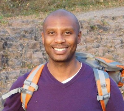 Cyrus Hamilton-Ferguson smiling outdoors, wearing a backpack