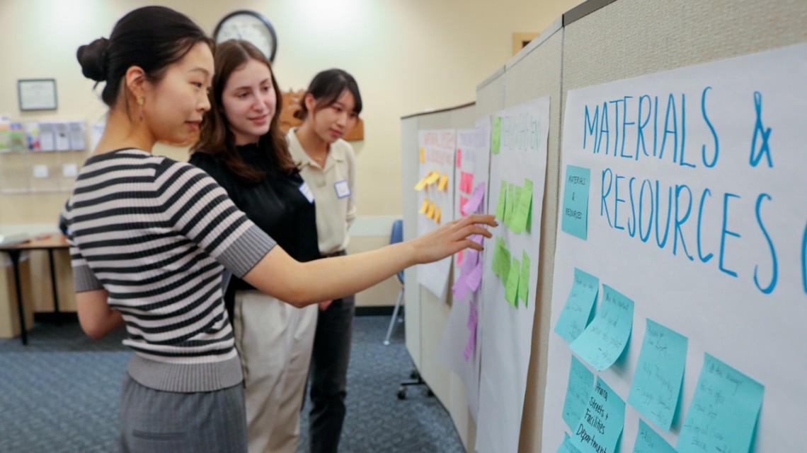 CUSD Sustainable City team members Isabella Zhi ’24 (left), Madeline Richmond, M.Eng. ’23 and Yuxi Wei, M.Eng. ’23 review notes at a March 2023 workshop at Tompkins County Public Library that brought together key stakeholders for the LEED certification project.